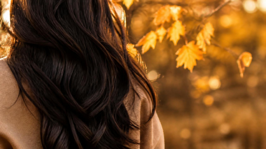 Woman with long dark hair in soft autumn light, seasonal hair shedding advice at Hair Nova Finchley